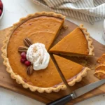 A beautifully presented slice of Patti Labelle's sweet potato pie with a golden crust, creamy filling, and a dusting of cinnamon.