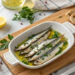 Delicious boquerones served on a white dish with crusty bread, lemon, and a glass of Albariño wine