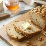 Golden wheatberry bread with melted butter on a rustic wooden cutting board