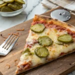 Slice of pizza with tangy pickles on a rustic wooden board