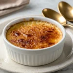 Elegant crab brûlée with a golden caramelized sugar crust served on a white plate with a gold spoon