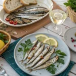 Mediterranean table setting featuring boquerones and anchovies, garnished with lemon, parsley, and olives, perfect for seafood lovers.