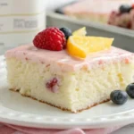 Freshly baked kefir sheet cake topped with berries and powdered sugar, showcasing a light and fluffy texture.