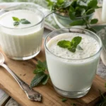 Fresh glasses of kefir and buttermilk side by side on a wooden table, showing the creamy textures of these healthy drinks.