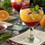 Glass of Mangria with fresh fruits and mint, placed on a rustic wooden table.